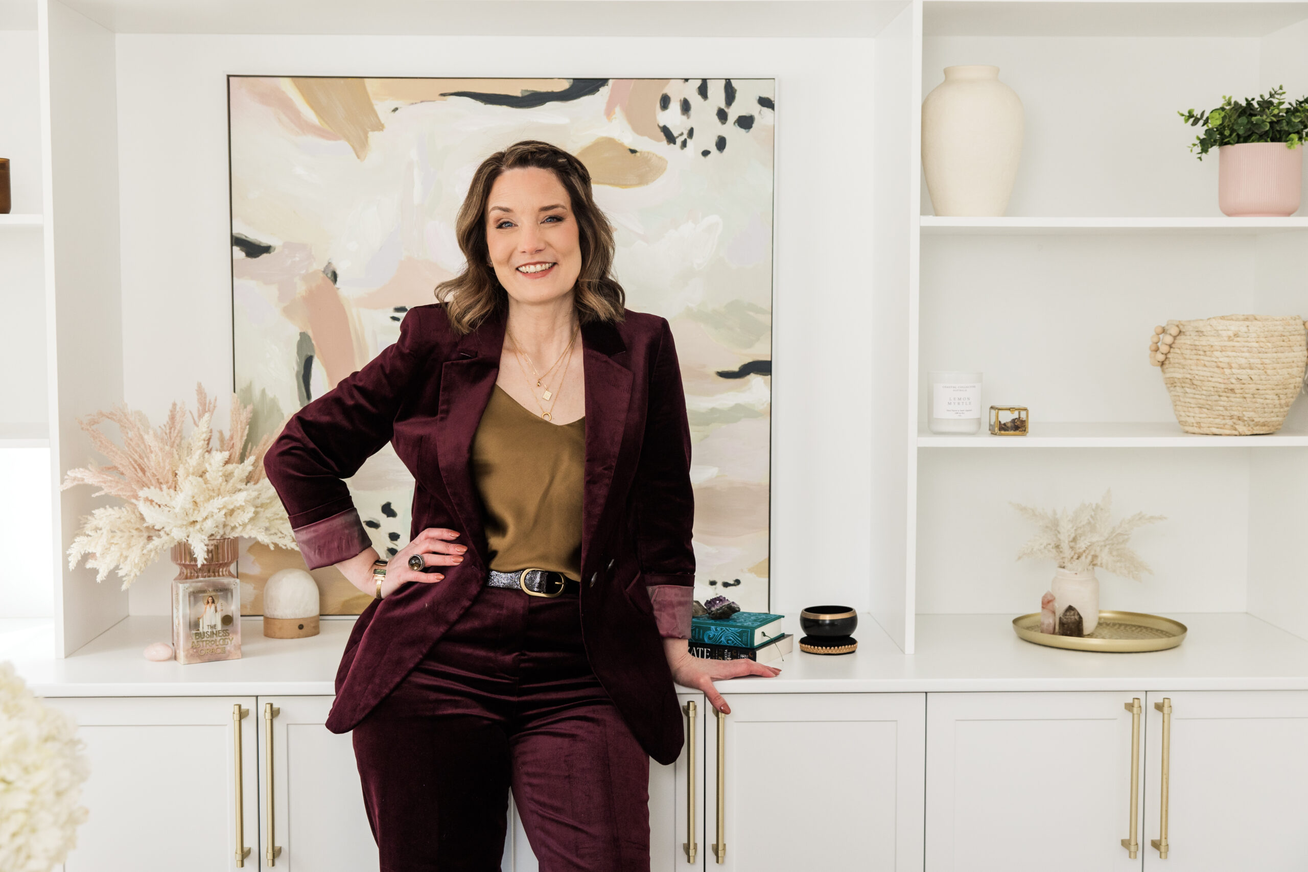 Kathryn Hocking with the Business Astrology Oracle Deck on styled shelving in brand colours