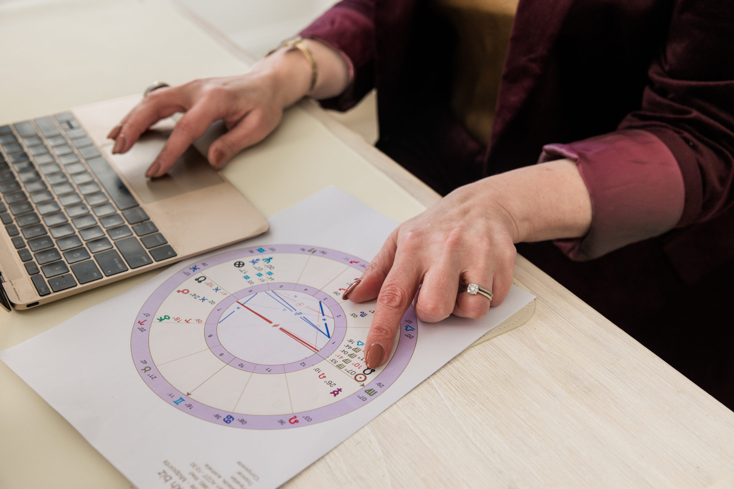 A natal chart being read alongside a laptop