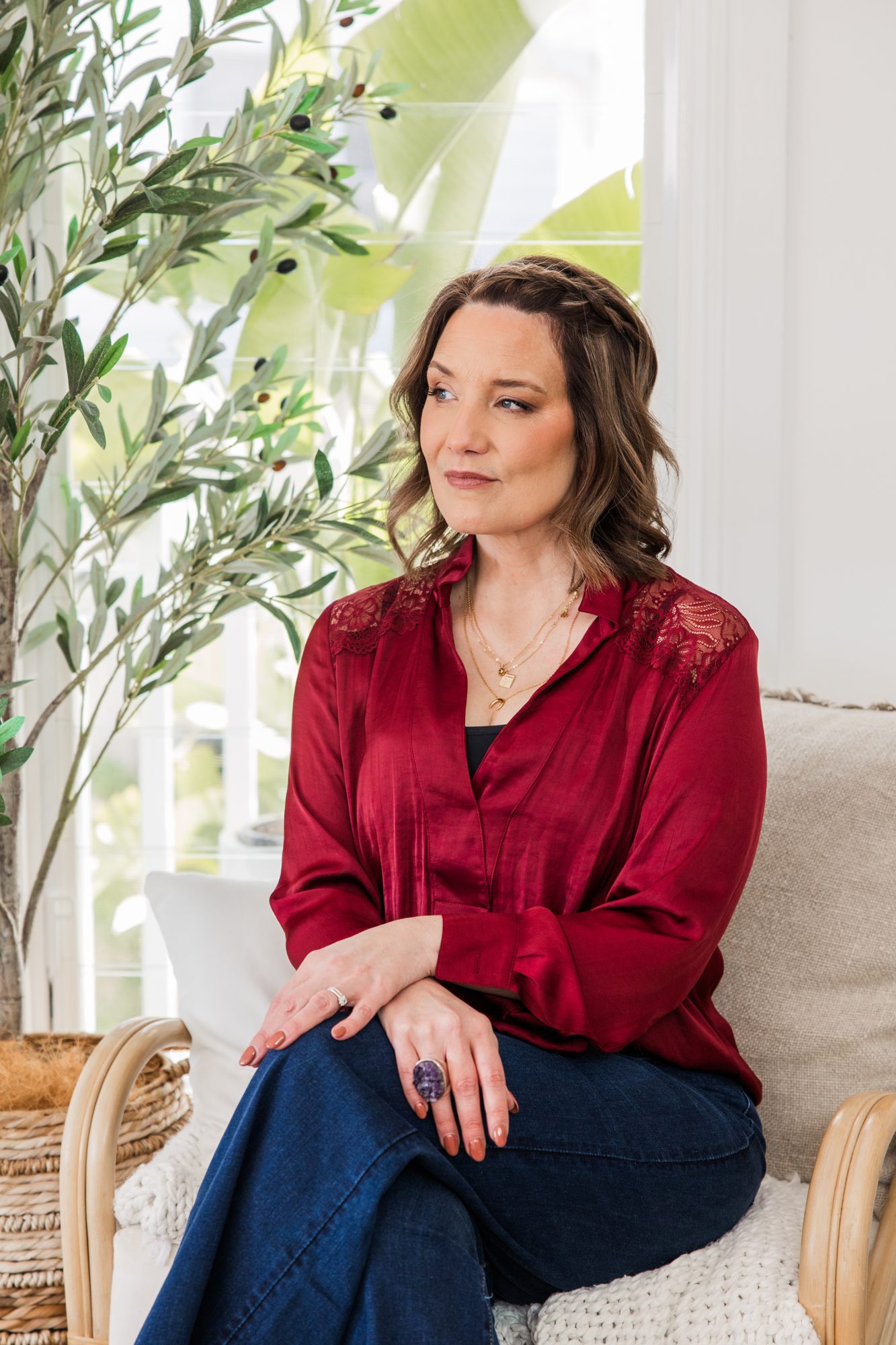 Kathryn Hocking in a burgundy blouse, seated by a window